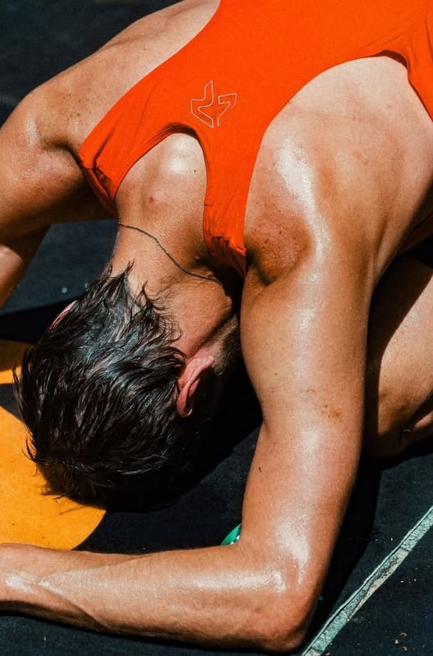 Close-up of an athlete in an orange top resting face-down on a track